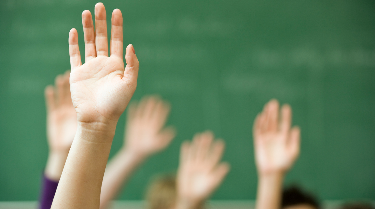 Elever rækker hånden op i en skoleklasse